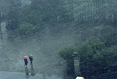 Two lone figures with umbrellas caught in rain storm, Dublin, Republic of Ireland, Europe